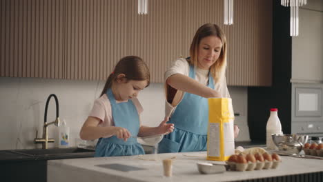 adult-woman-and-little-girl-are-cooking-in-sunday-in-home-sifting-flour-for-pancakes-mother-and-daughter
